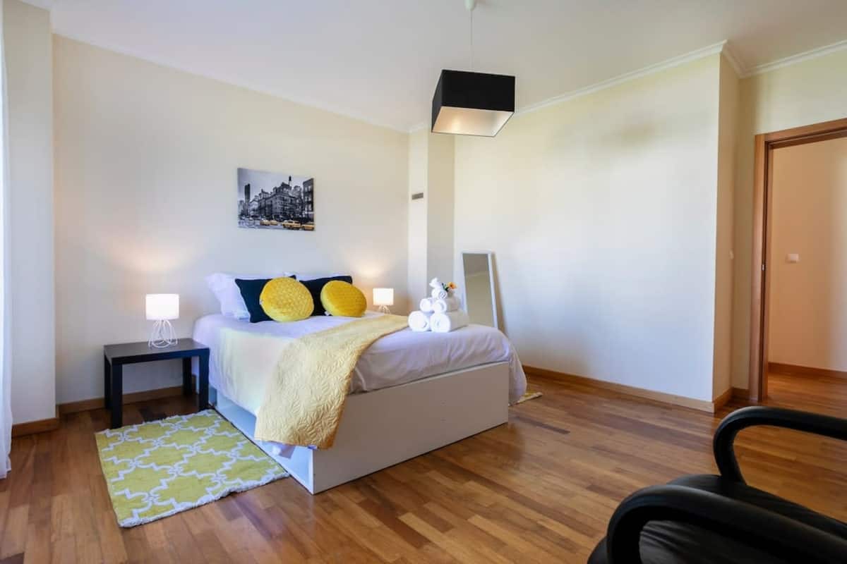 Spacious double bedroom with yellow accents and hardwood floors