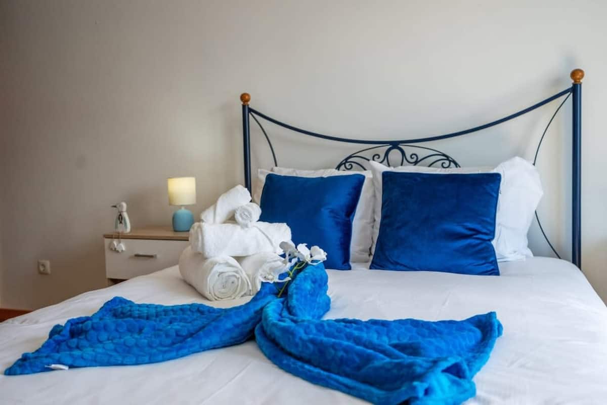 Double bed with blue cushions and folded towels