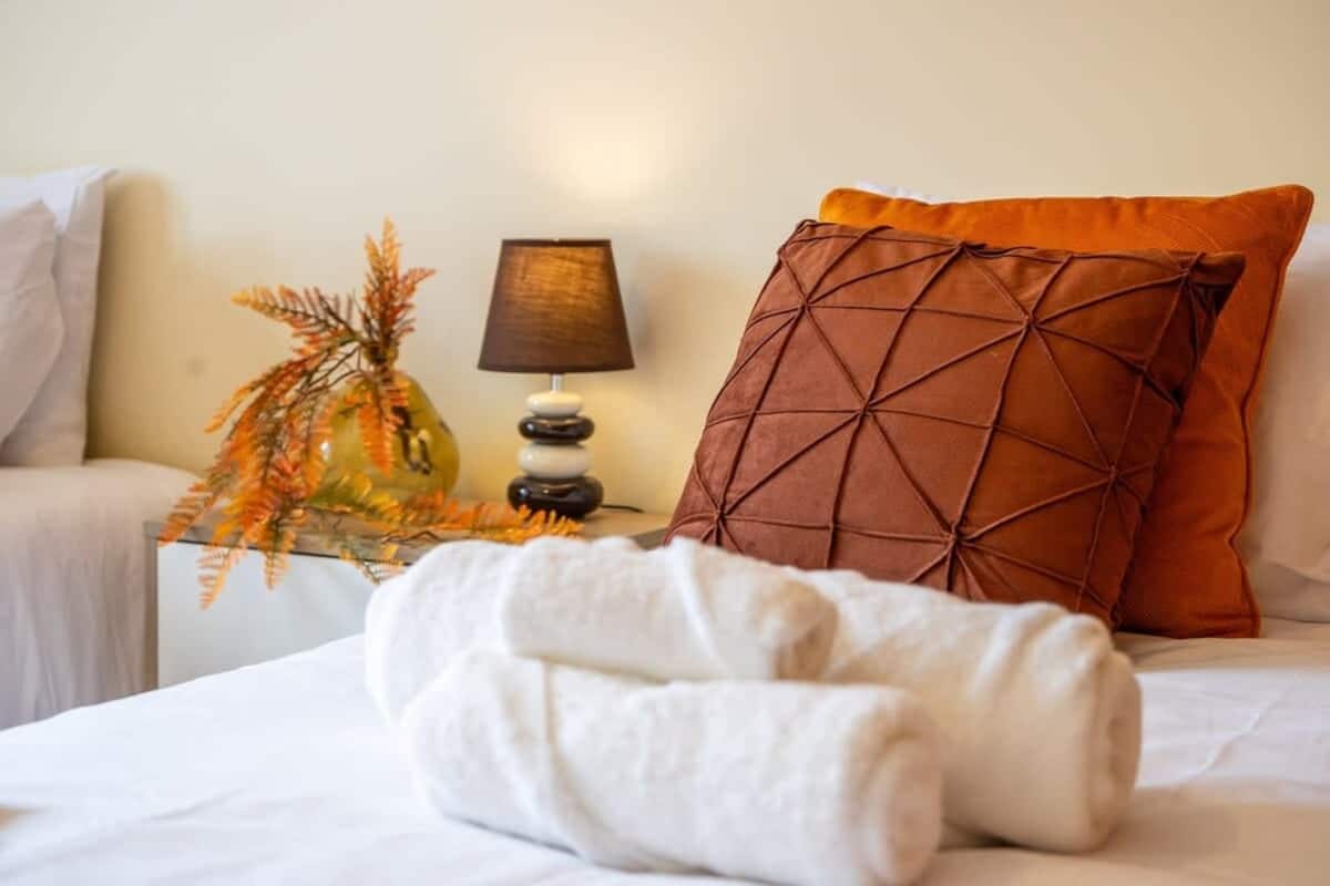 Bedroom detail with brown cushions, bedside lighting and folded towels