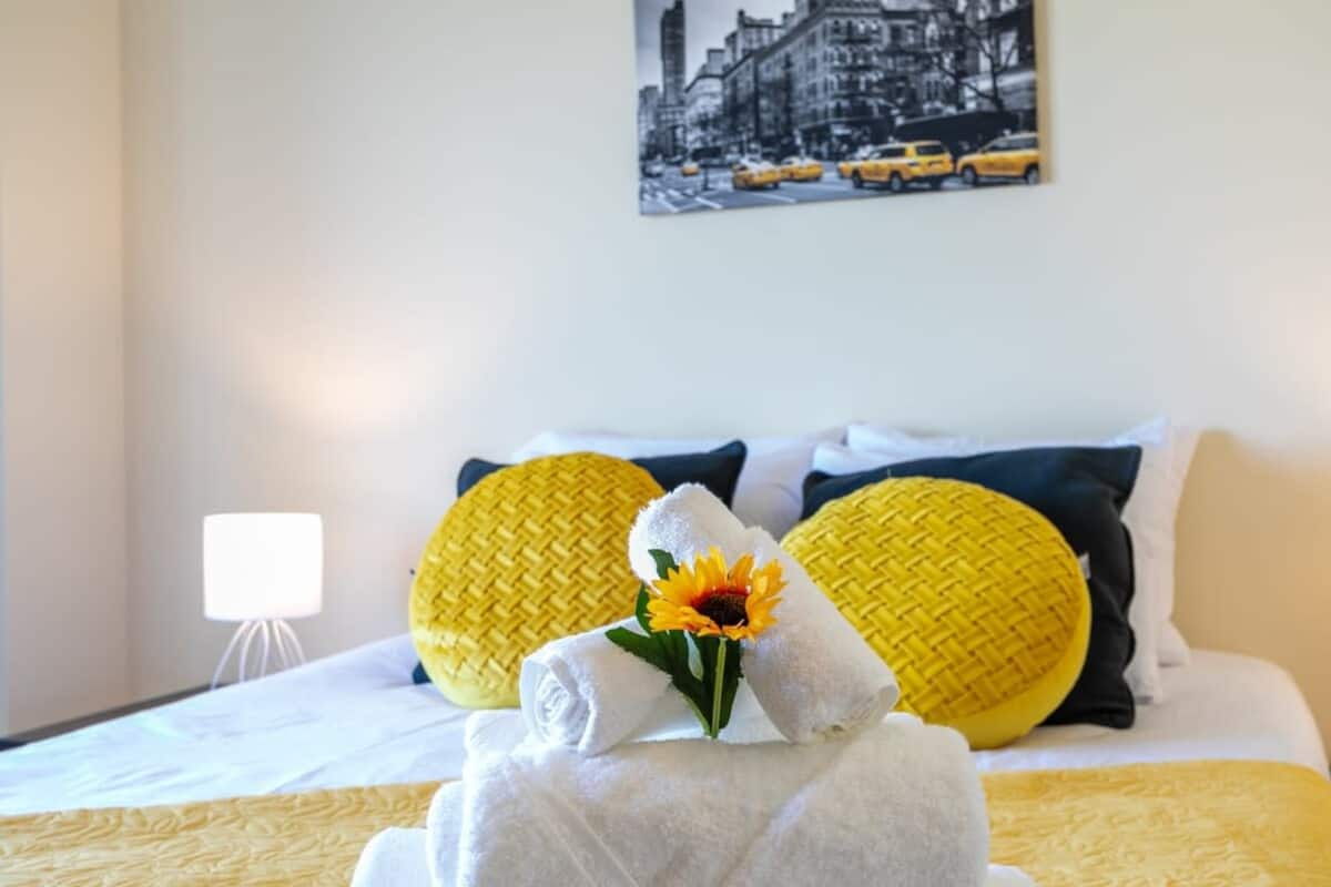 Yellow-accented double bed prepared with towels
